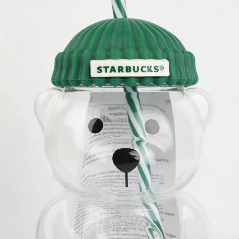 Close-up of the Starbucks Bearista Bear glass tumbler showing the green lid, STARBUCKS branding, and striped straw