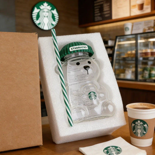 Starbucks bear-shaped bottle with straw and cup on a wooden surface