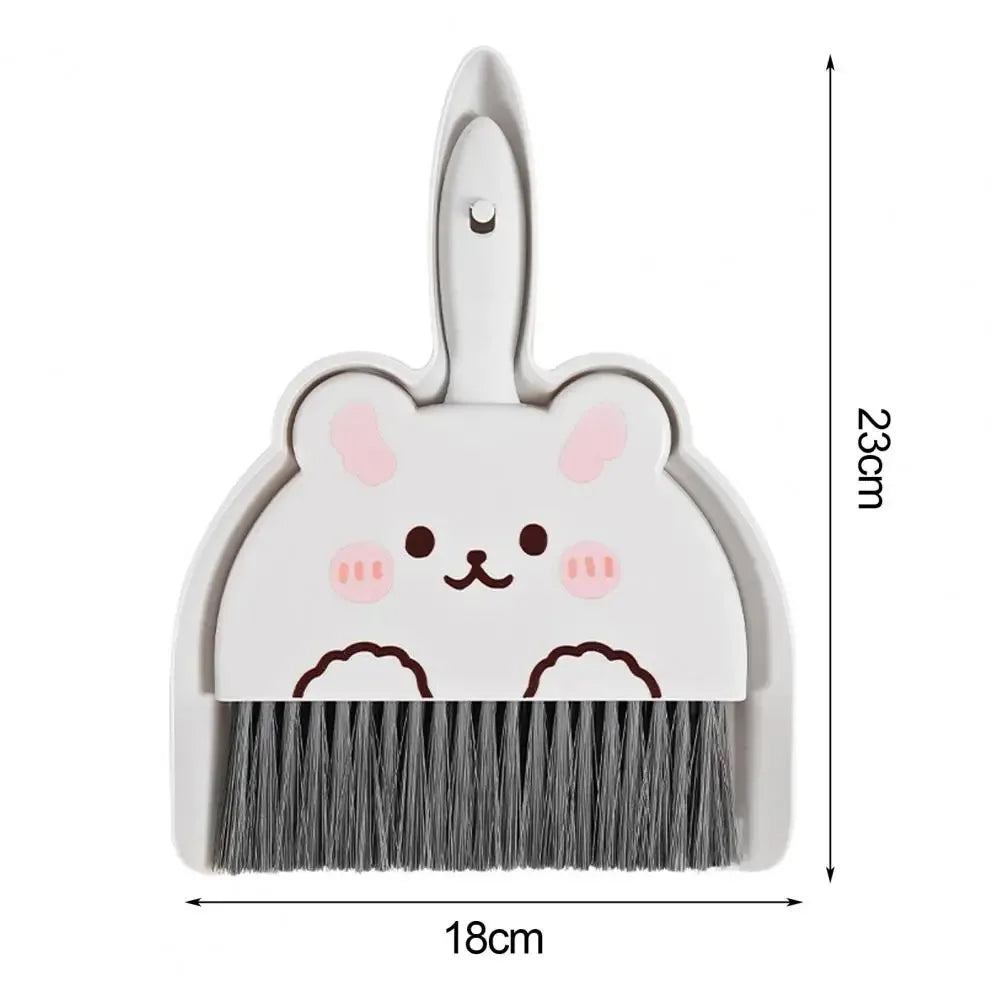A small white dustpan and brush set with a cute cartoon bunny face on the dustpan, shown on a white background with dimension lines indicating 18cm width and 23cm height.