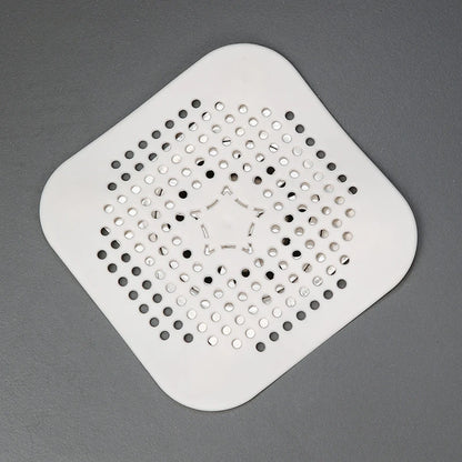 Square white drain cover with perforated design on a gray background