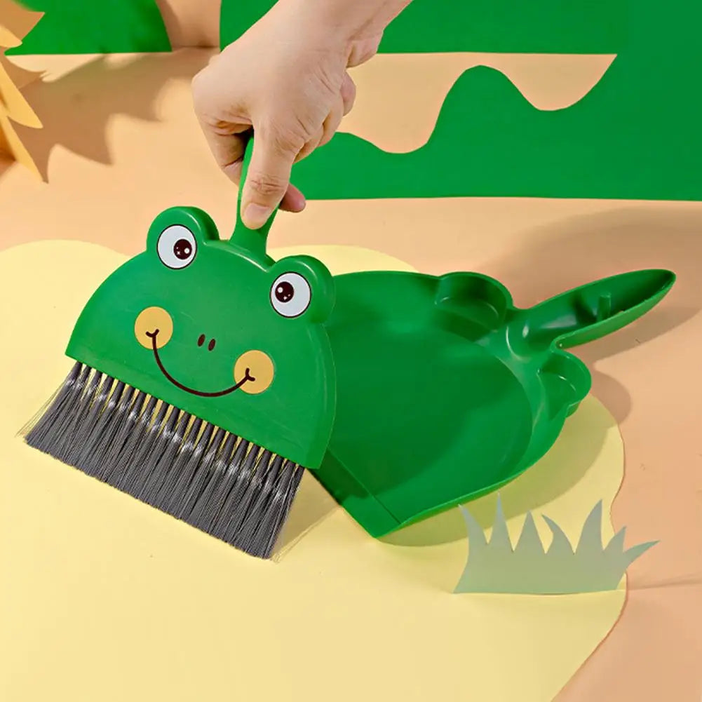 Green frog-shaped broom and dustpan set on a beige background