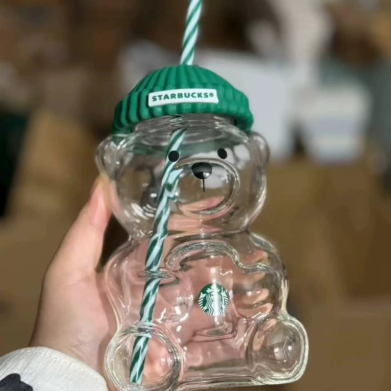 Clear bear-shaped Starbucks cup with green lid held by a hand against a blurred background