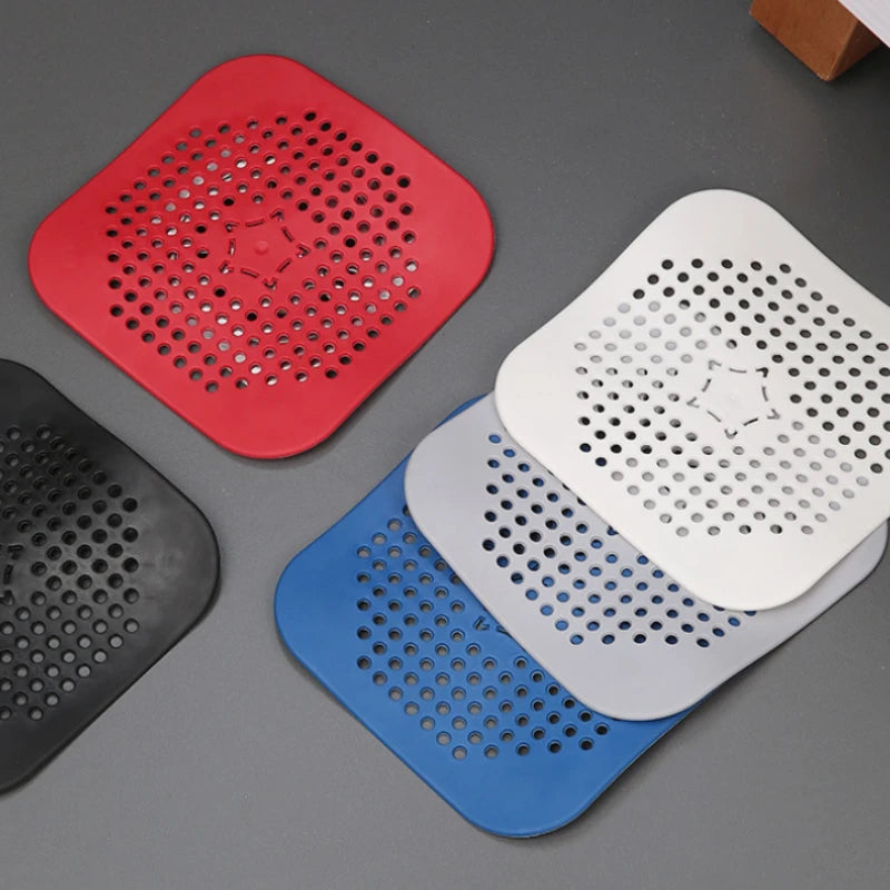 Four square silicone drain hair catchers in red, white, blue, and black
