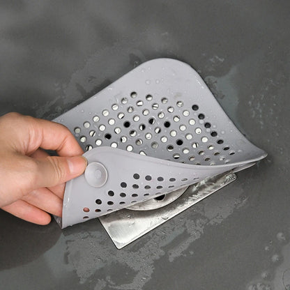 Gray silicone strainer held by a hand over a sink.