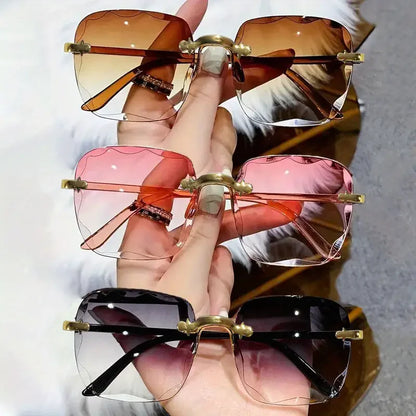 Three pairs of sunglasses held by a hand with different colored lenses and gold frames.